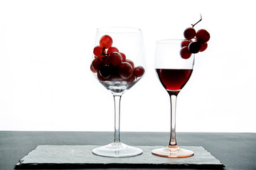 Crystal glasses with red grape and tasty wine on white background