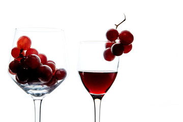 Crystal glasses with red grape and tasty wine on white background