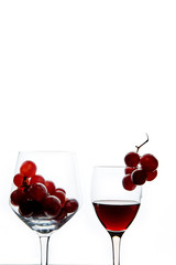 Crystal glasses with red grape and tasty wine on white background