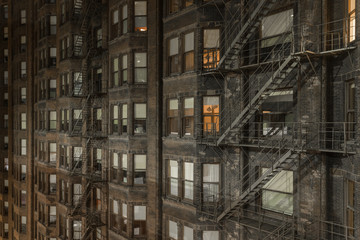 Side of vintage skyscraper with bay windows and steel fire escapes