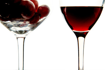 Crystal glasses with red grape and tasty wine on white background