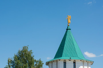 Weather vane in the form of trumpeting angel on roof. 