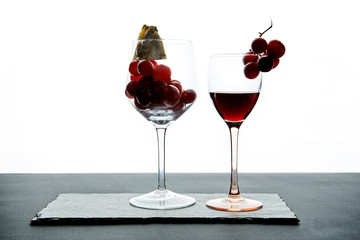 Composition of glasses with ripe grape and red wine served on slate board