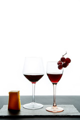Composition of glasses with ripe grape and red wine served on slate board