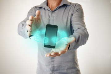 Man with phone floating between his hands and holographic digital  icons. Futuristic tecnology and business communication concept image.