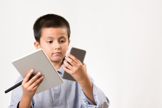 Young boy wearing his dads shirt pretending to be businessman with digital devices and pen. Childhood education, learning play concept image with copy space for text.