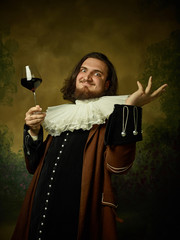 Young man as a medieval knight on dark studio background. Portrait of male model in retro costume....