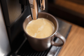 Espresso machine pouring coffee in brown cup.