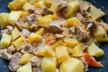 Potatoes with pork stewed in a pan. Vegetables and meat for dinner.