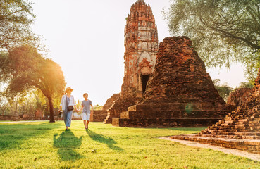 Mother and son tourists walking hand in hand in atcient Wat Chaiwatthanaram Buddhist temple ruines in holy city Ayutthaya, Thailand  in Auyttaya - obrazy, fototapety, plakaty