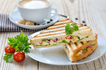 Grillsandwich mit gegrillter Hähnchenbrust, Tomaten, Zwiebeln und Salat, dazu ein Cappuccino - ...