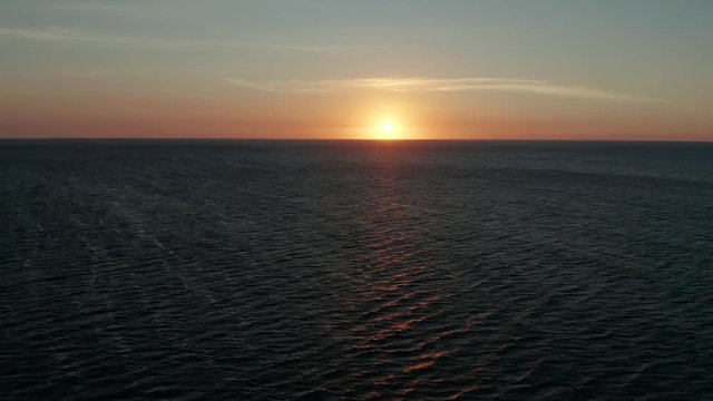 Colorful sunset above the sea surface with waves, aerial drone. Sunset over ocean. Seascap, Summer and travel vacation concept