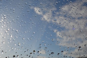 Raindrops on the window glass.The sun illuminates the outgoing clouds,weather change.