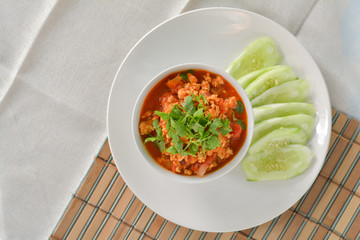 Top view delicious Northern Thai meat and tomato spicy dip in white bowl served with slice cucumber