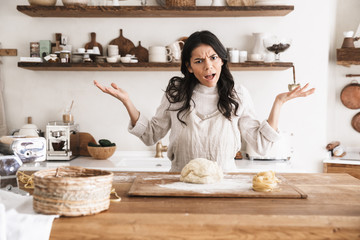 Portrait of outraged european woman making homemade pasta of dough in kitchen at home
