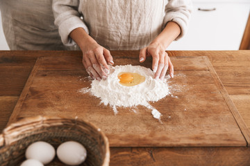 Portrait of attractive couple wearing aprons cooking pastry with flour and eggs in kitchen at home