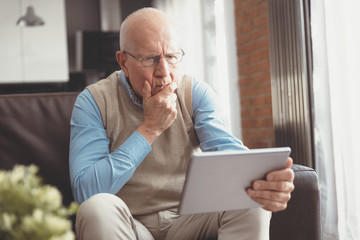 Confused senior man using a digital tablet