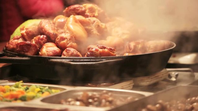 Meat is fried on a big frying pan at street fair