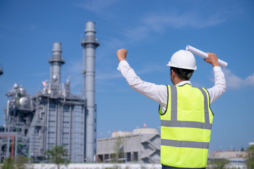 Industrial engineer Success work standing in front of a large Power plant with safety helmet with gas turbine industry plant background