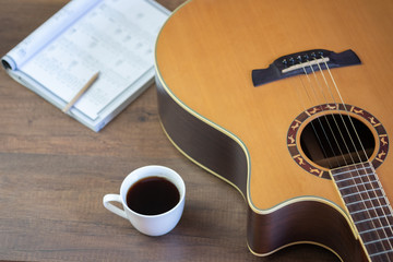 Acoustic guitar and Write musical notes and cup of coffee on table wooden background