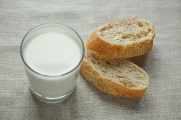 Glass of milk with fresh bread on a tablecloth. 