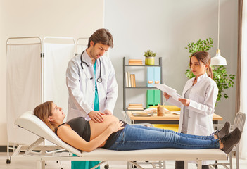 Pregnant woman in the control and man doctor looking the baby healthy with his assistance, close up sick bed.