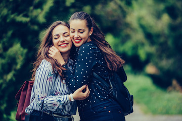 Two emotional happy women friends hugging each other outdoors