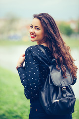 Fototapeta premium Portrait of a cheerful smiling girl with backpack while walking outdoor