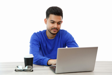 a young guy sitting at a laptop in search of work on the Internet , doing business in the global...