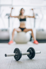 Attractive muscular fitness woman doing exercise with dumbbells in gym