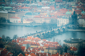 Obraz premium Beutiful view of the historical architectural buildings with red roofs and Charles bridge with tourists. View from an observation deck in Prague, Czhech Republic. Aerial top view