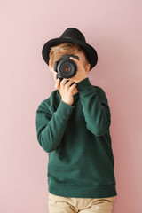 Cute little photographer with professional camera on color background