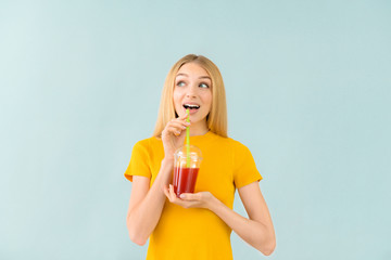 Beautiful young woman with fresh juice on light background