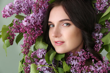 Face of beautiful young woman surrounded with lilac flowers