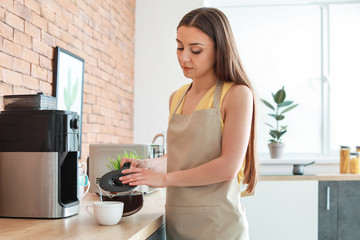 Beautiful woman using coffee machine in kitchen