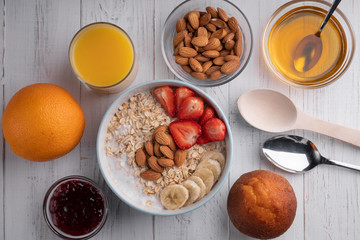 Traditional breakfast with oatmeal, muffin, juice, jam, nuts, honey and fruits. White background. Top view