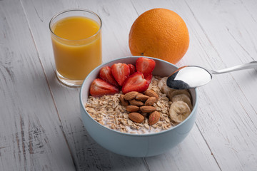Breakfast - oatmeal with bananas, strawberry, nuts and juice. Top view. Healthy food. Muesli. Organic. Diet