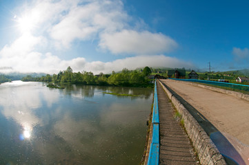 Naklejka premium beautiful mountain river of spring sunny day and the bridge through it
