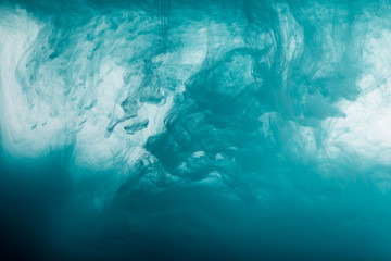 Close up view of turquoise watercolor paint swirls in water