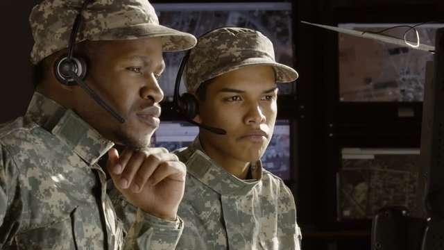 2 military drone operators consulting in front of a computer