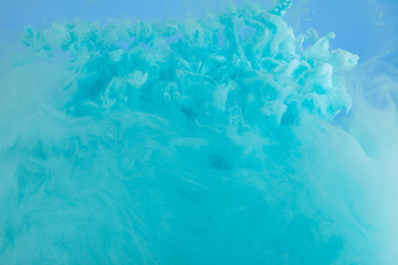 Fototapeta na wymiar Close up view of turquoise smoky paint swirls isolated on blue