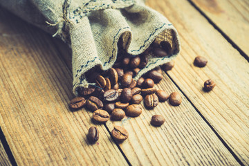 Coffee beans in sack on the rustic wooden background. Selective focus. Shallow depth of field.