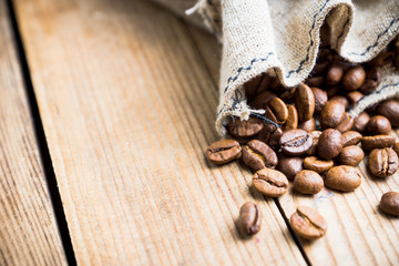 Coffee beans in sack on the rustic wooden background. Selective focus. Shallow depth of field.