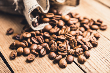 Coffee beans in sack on the rustic wooden background. Selective focus. Shallow depth of field.