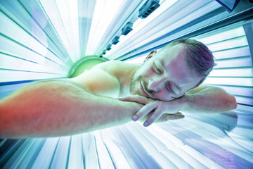 Smiling young man in solarium relaxing