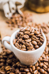 Coffee beans in white cup on the rustic wooden background. Selective focus. Shallow depth of field.