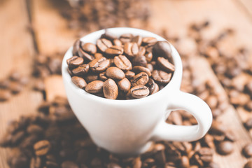 Coffee beans in white cup on the rustic wooden background. Selective focus. Shallow depth of field.