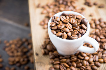 Coffee beans in white cup on the rustic wooden background. Selective focus. Shallow depth of field.