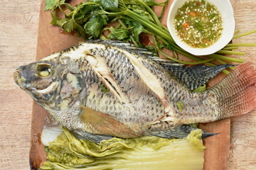 steamed mango fish with vegetable dipping spicy sauce on wooden chop block