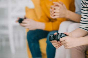 cropped view of child holding joystick while sitting near mother and brother